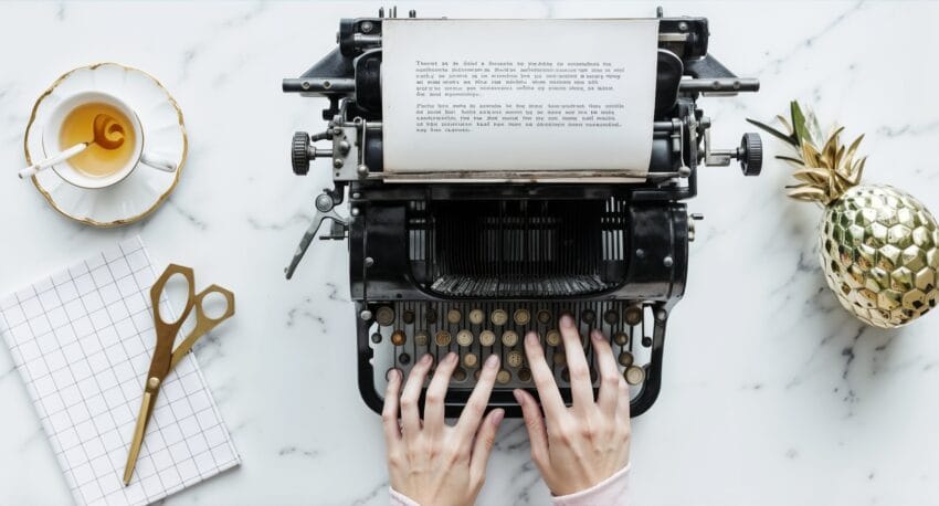 a typewriter and 2 woman's hands typing